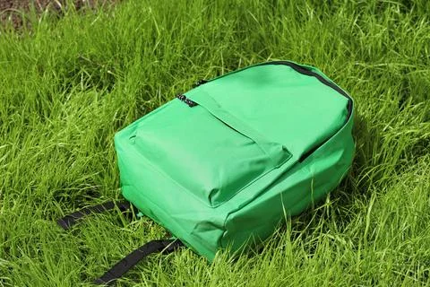 Green school backpack on grass outdoors Stock Photos
