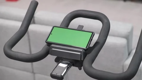 Green screen cell phone on a stationary bike trainer exercise machine 스톡 동영상 312076830