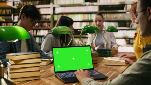 Green screen chroma key on laptop in front of study group at library table Stock Footage 336359345