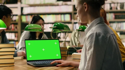 Green screen chroma key on laptop in front of study group at library table Stockbeeldmateriaal 336361723