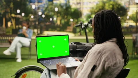 Green screen chroma key on laptop held by delivery courier in urban park Stock Footage 343500755