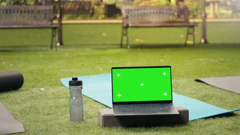 Green screen chroma key on laptop near yoga mats in green urban park Stock Footage 346020623