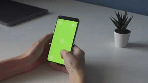 Green screen chroma key on smartphone on white table with small plant Stock Footage 167826437
