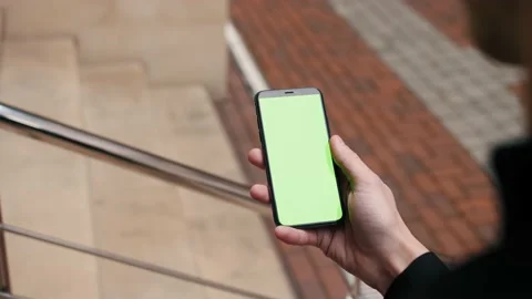Green screen, Close-up view of a person holding a smartphone swiping pages on Stock Footage 143354521