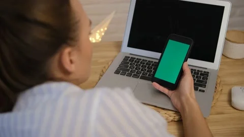 Green screen of the computer and phone. The girl is sitting at the table and bro Stock Footage 148532882