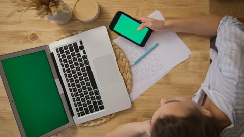 Green screen of the computer and phone. The girl is lying at the table and surfi Video stock 149285540