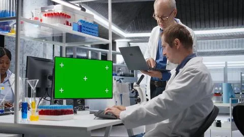 Green screen on computer display with colleagues working in biotechnology lab Stockfoto's