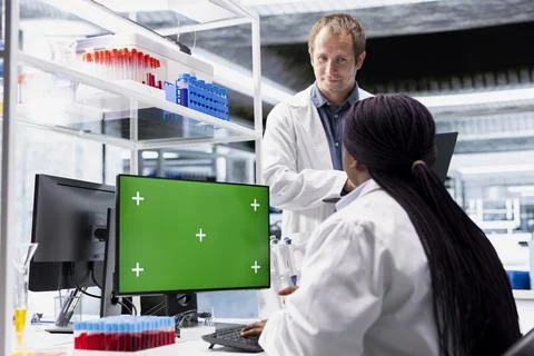 Green screen on computer display with colleagues working in biotechnology lab Stock Photos