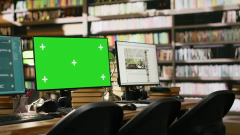 Green screen desktop with multiple monitors showing interfaces in library Stock Footage 337230635