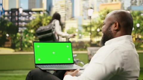 Green screen isolated mockup on laptop held against blurred city park Vídeo Stock 343501197