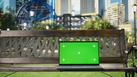 Green screen isolated mockup laptop on wooden bench placed in urban park Stock Footage 343502190
