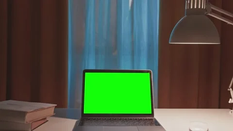Green screen laptop computer sitting on a home work desk next to a desk lamp. Stock Footage 148749058