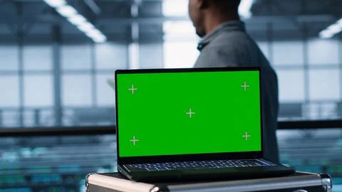 Green screen laptop in front of data center engineers inspecting servers Foto stock