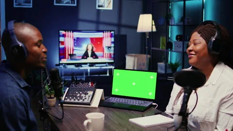 Green screen laptop next to vlogger show host and guest talking in neon lights Stock Footage 261766069