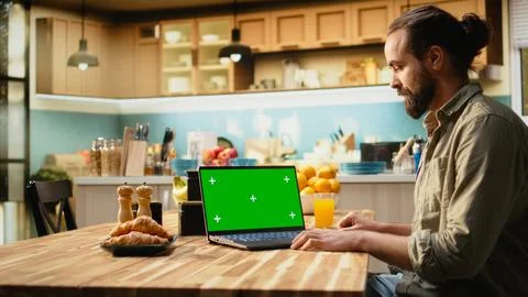 Green screen on laptop screen with analytics data at the kitchen table 스톡 사진