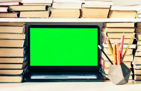 Green screen laptop, stack of books, notebook and pencils on white table, edu Stock Photos