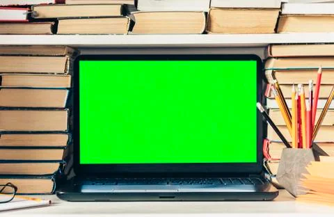 Green screen laptop, stack of books, notebook and pencils on white table, edu Stock Photos