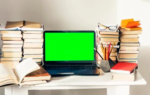 Green screen laptop, stack of books, notebook and pencils on white table, edu Stock Photos