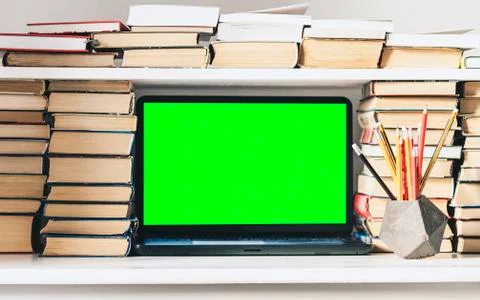 Green screen laptop, stack of books, notebook and pencils on white table, edu Stock Photos