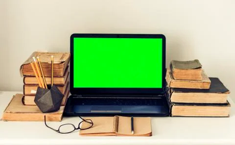 Green screen laptop, stack of old books, notebook and pencils on white table, Stock Photos