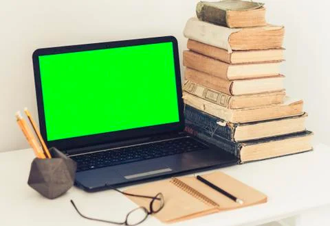 Green screen laptop, stack of old books, notebook and pencils on white table, Stock Photos