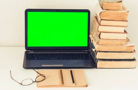 Green screen laptop, stack of old books, notebook and pencils on white table, Stock Photos