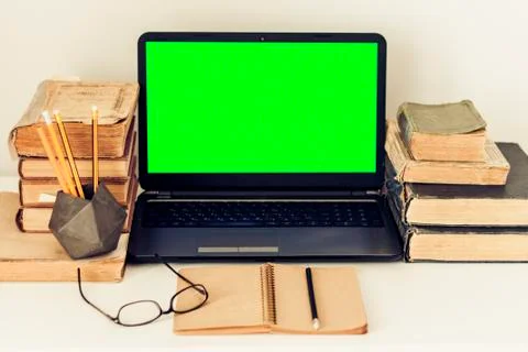 Green screen laptop, stack of old books, notebook and pencils on white table, Stock Photos