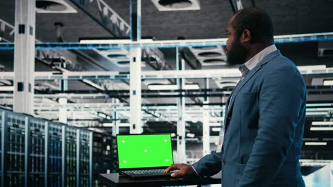 Green screen laptop used by server hub programmer to monitor rigs Stock Footage 330030176
