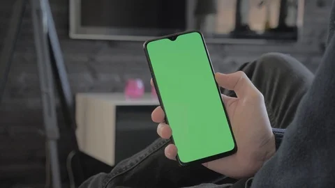 Green screen - Man at home sitting on a couch looking at a smartphone. Stock Footage 106038196