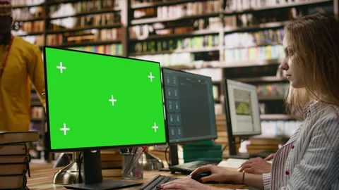 Green screen mockup on computer desktop near student at shared library table 스톡 동영상 337229144