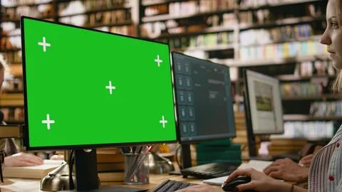 Green screen mockup on computer desktop near student at shared library table 写真素材