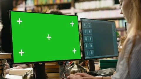 Green screen mockup on computer desktop near student at shared library table 写真素材