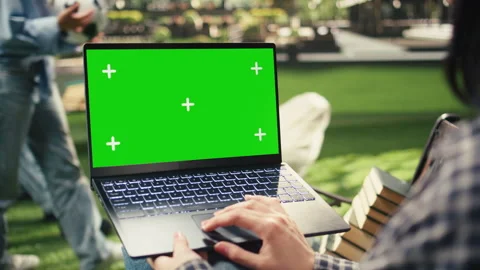 Green screen mockup sitting on bench with laptop as student works outdoors Stock Footage 340810037