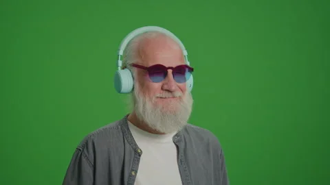 Green Screen. Modern Old Man Listens to Music in Headphones. Stock Footage 243145886