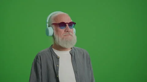 Green Screen. Modern Old Man Listens to Music in Headphones. Stock Footage 243473933