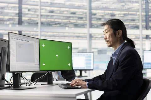 Green screen PC used by man doing yield enhancement, tracking microchip defects Foto stock