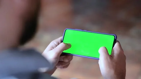 Green screen phone mock up in the hands of a man playing games on a smartphone Stock Footage 155381771