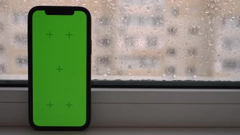 Green Screen Phone Resting on a Windowsill During a Soft Rainy Afternoon Stock Footage 345550603