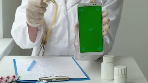 Green screen phone in vertical position and doctor pointing on it in clinic Stock Footage 250663163