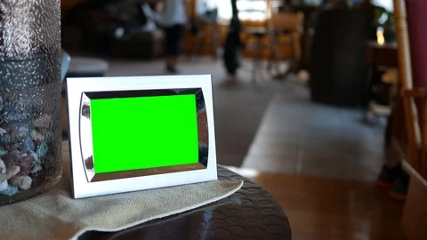 A green screen picture frame sitting on an end table with blurry people in backg Stock Footage 98793339