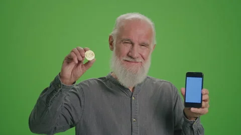 Green Screen. Portrait of an Old Man with a Phone with Blue Screen and BTC Coin. Video stock 263393358