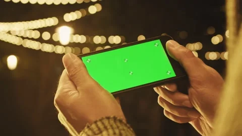 Green screen smartphone. A man's hand holds a phone. Scrolling on the green Stock Footage 155689431