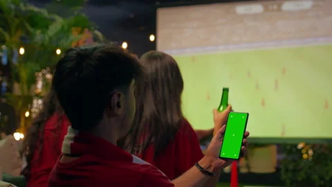 Green screen smartphone mockup used by man viewing soccer match Stock Footage 346781040