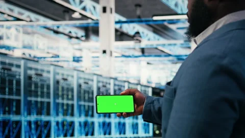 Green screen smartphone used by server farm worker to optimize electronics Stock Footage 330029786