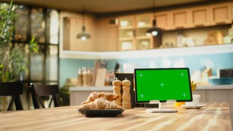 Green screen tablet, cozy kitchen interior, empty breakfast table with food Stock Photos