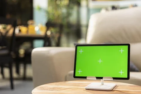 Green screen tablet, cozy open space interior, empty wooden table in living room Stock Photos