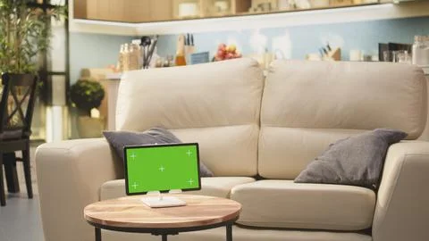 Green screen tablet, cozy open space interior, empty wooden table in living room Stock Photos