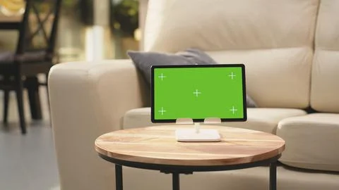 Green screen tablet, cozy open space interior, empty wooden table in living room Stock Photos