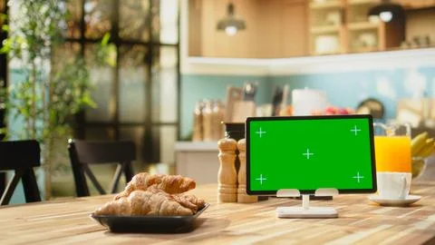 Green screen on tablet in kitchen interior design with empty wooden table Stock Photos