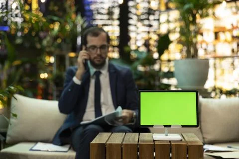 Green screen tablet mockup on stand with businessman on phone at night Foto stock